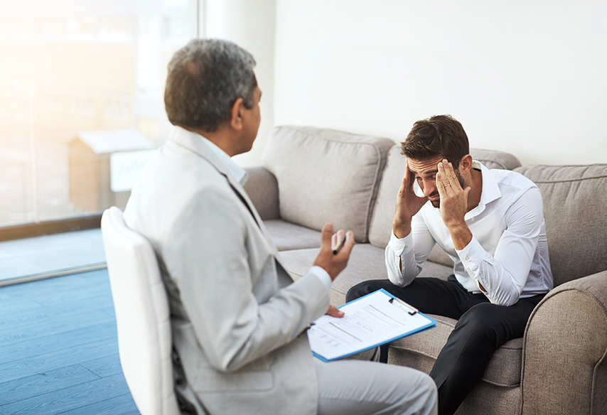 male doctor speaking with patient on couch